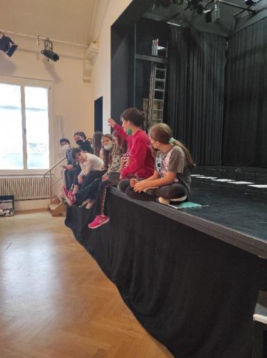 Mädchen* sitzen auf einer Bühne und quatschen.